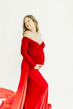 Stunning red maternity dress billows dramatically in studio photoshoot.