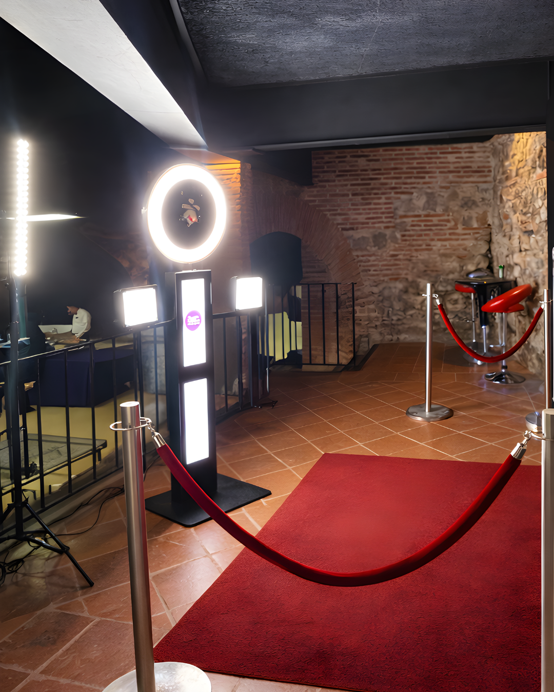 A series of connected rooms with red curved hammock-like structures installed in an industrial space with exposed brick walls.