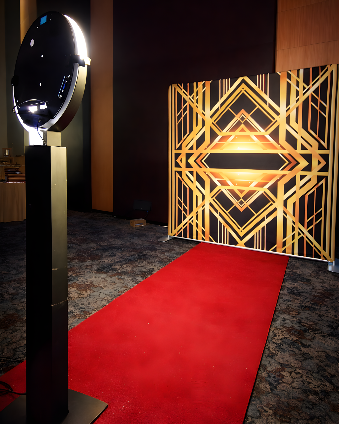 Art deco inspired geometric gold patterns illuminate a dark hallway with a dramatic red carpet leading the way.