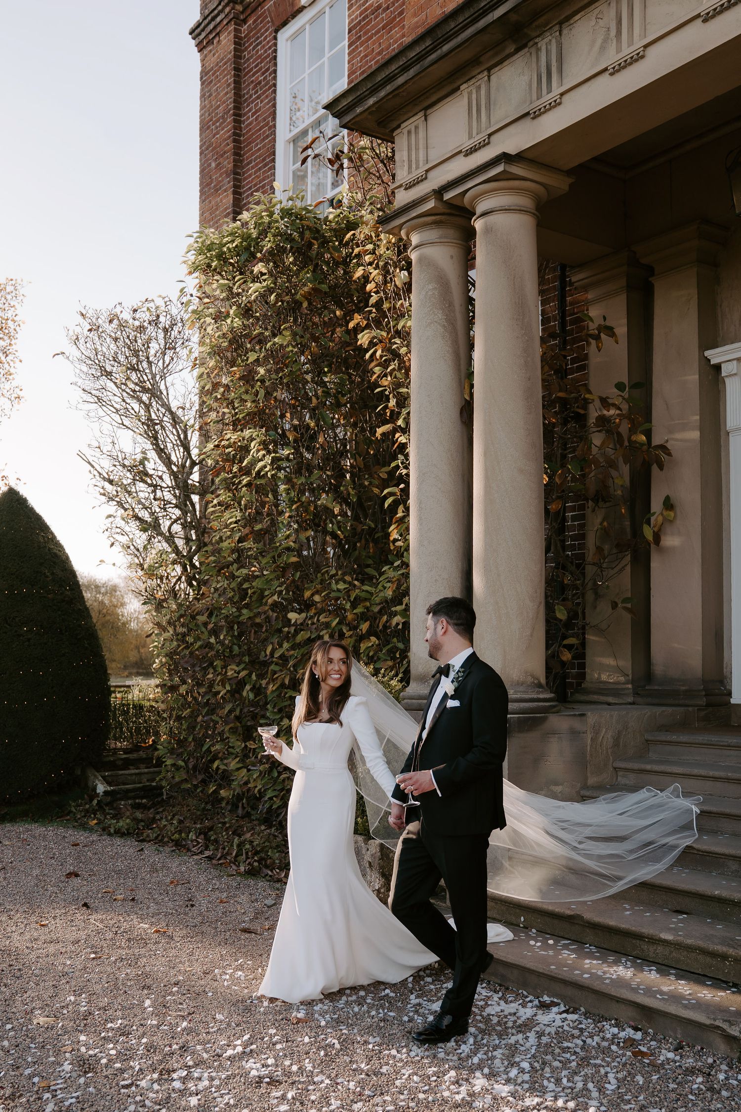 bride and groom smiling at each other and holding hands while descending stairs outside Iscoyd park