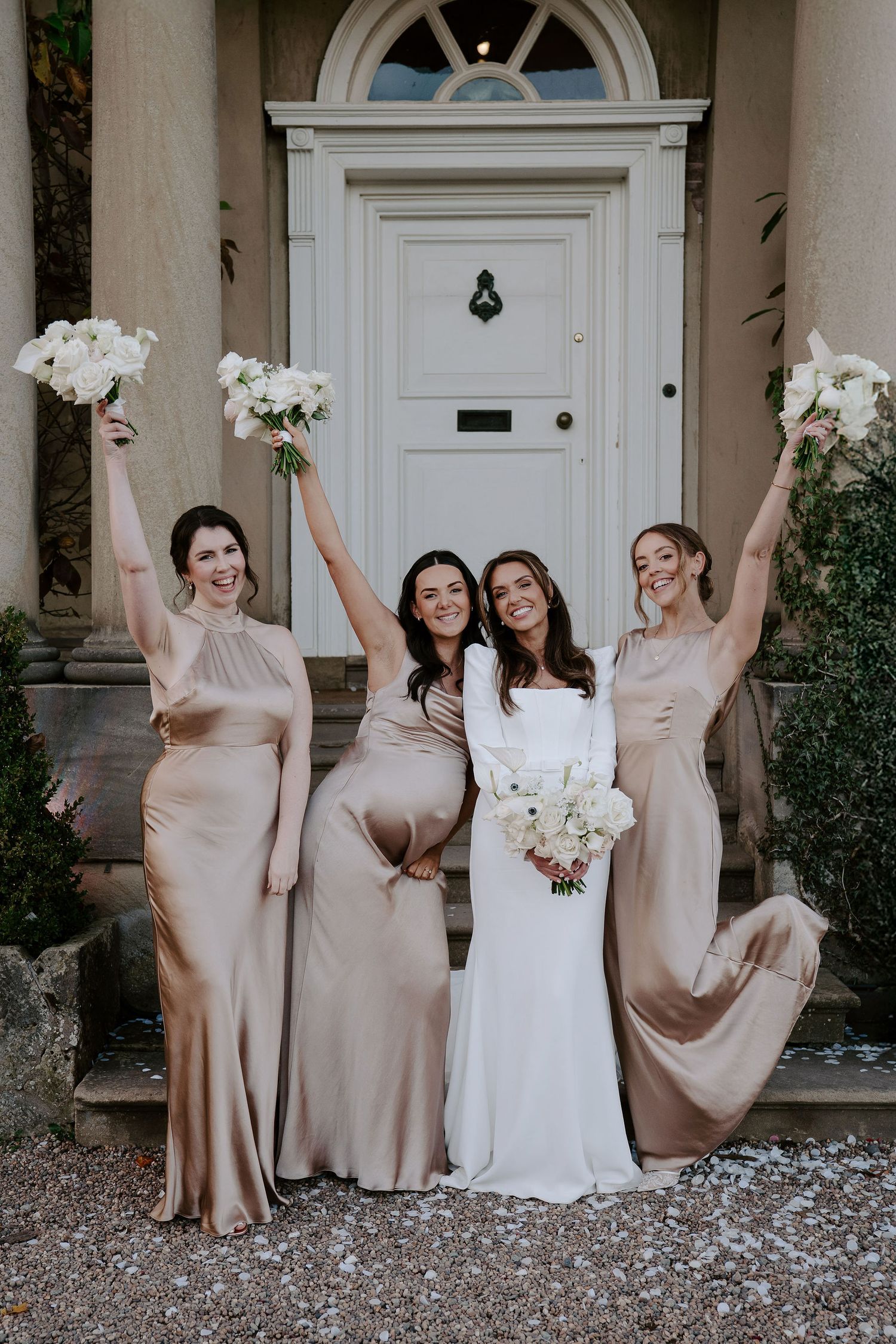 bride and bridesmaids throwing bouquets in the air laughing outside Iscoyd park