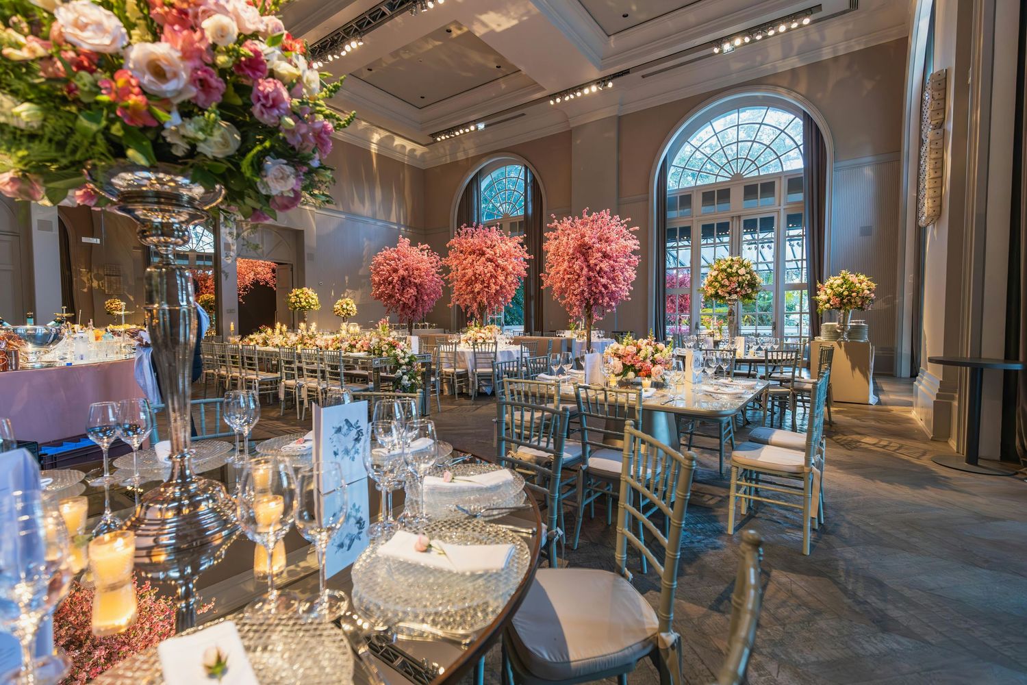 Elegant wedding reception venue with crystal chandeliers, floral arrangements, and luxurious table settings in a grand ballroom.