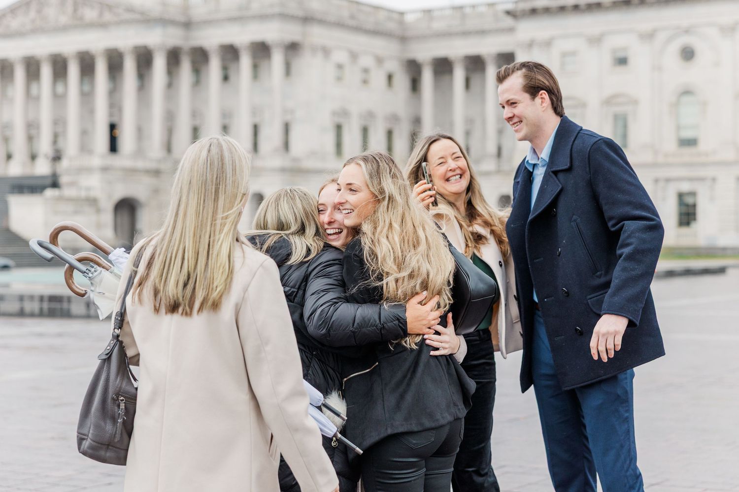 Family members share joyful moments together while walking outside a grand government building.