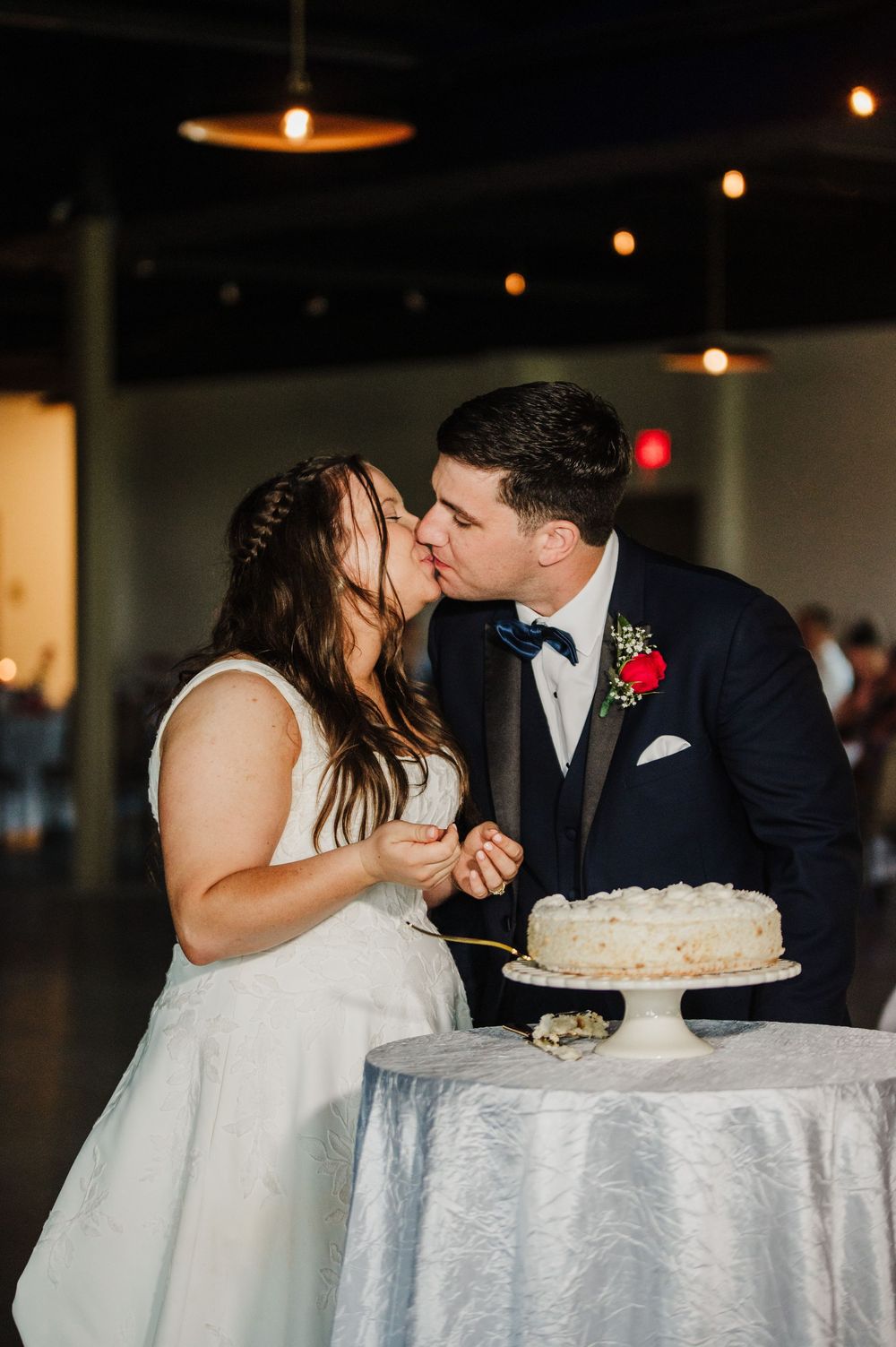 A couple shares intimate moments during their wedding reception while cutting and feeding each other cake.