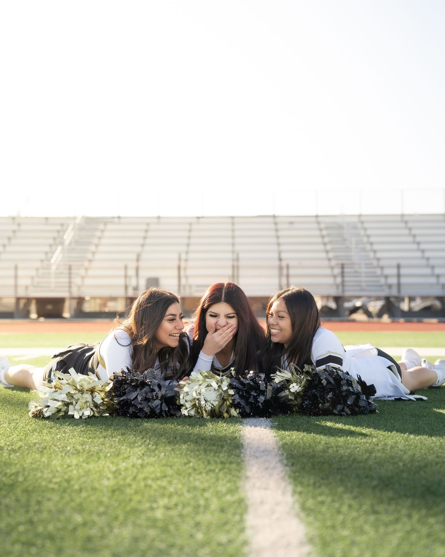 Cheerleaders tossing pom-poms in the air during outdoor group portrait