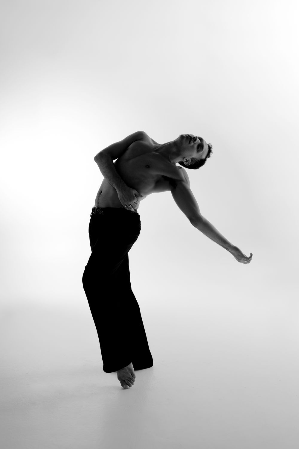 A sequence of black and white photos showing a person performing a backflip against a light background.