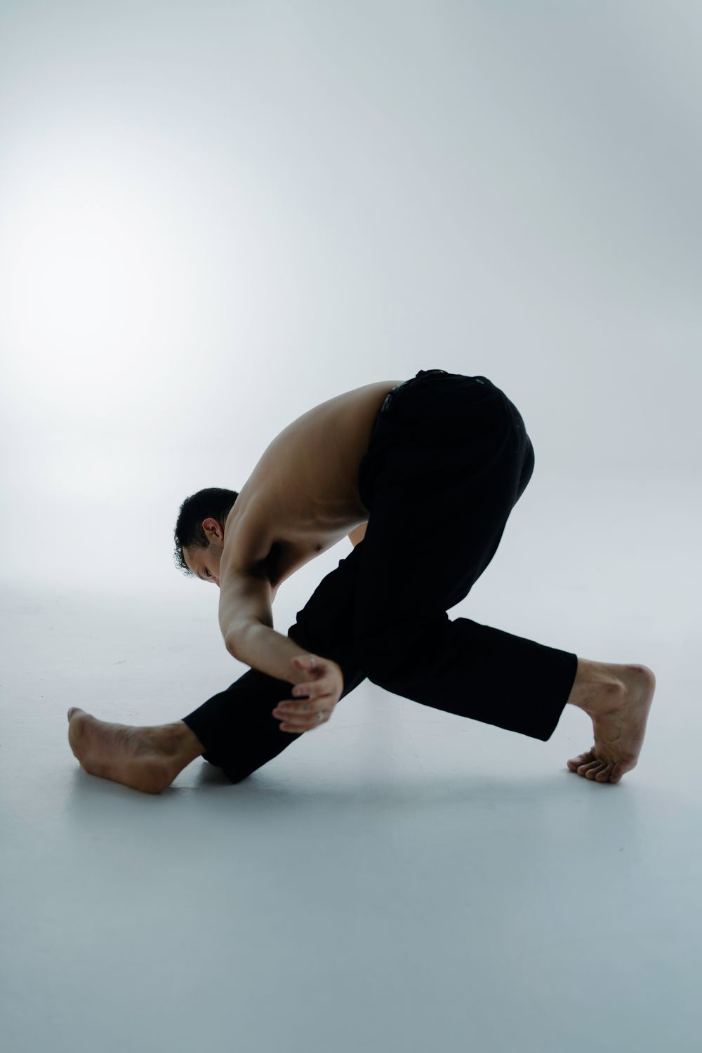 A sequence of dance movements showing a figure in black clothing performing a rolling motion on a white background.