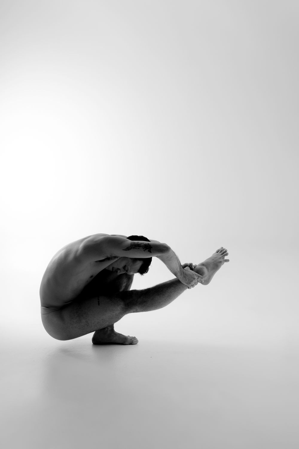 A series of minimalist black and white silhouettes showing a figure in various curled positions against a light background.