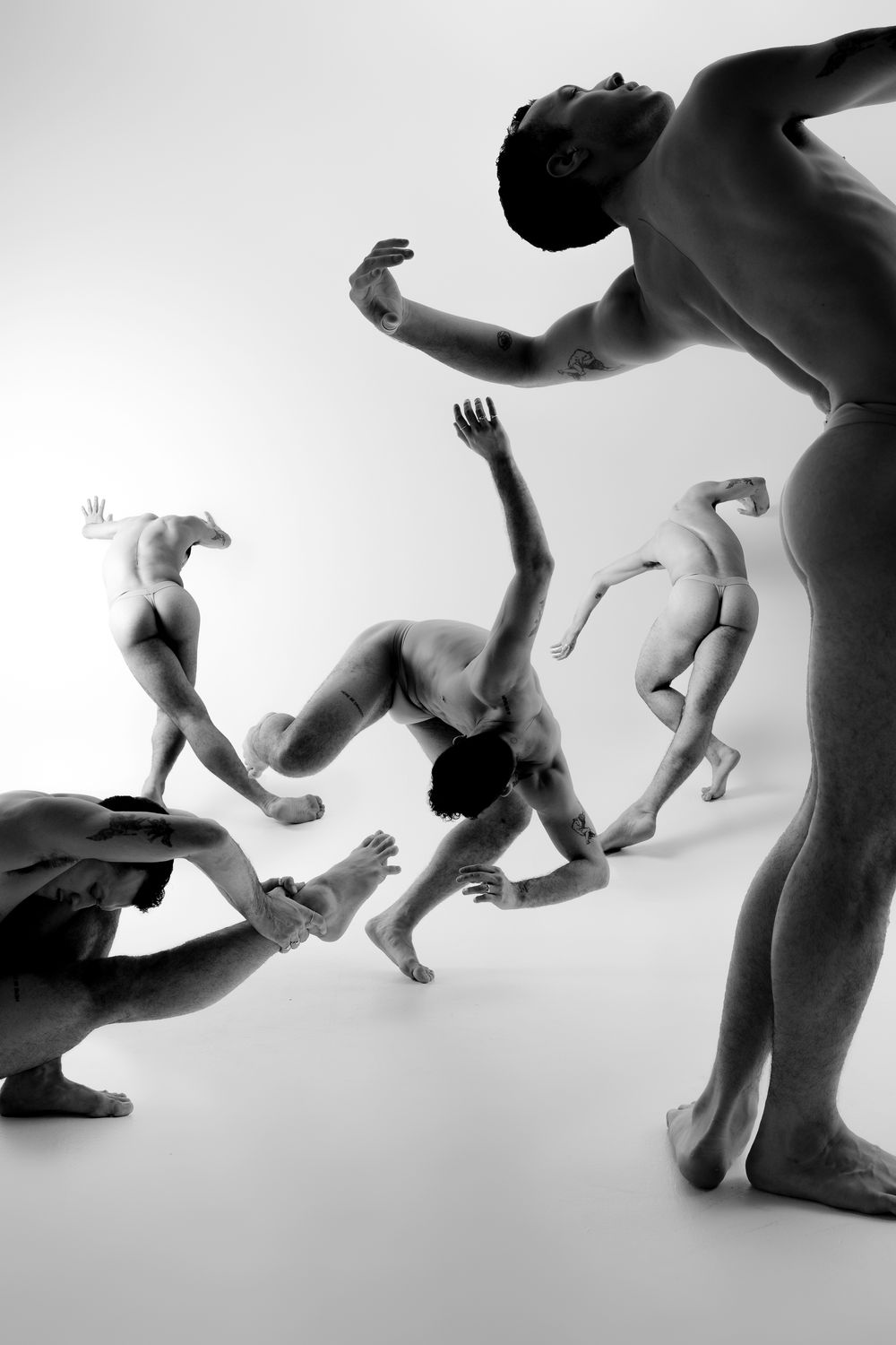 Dynamic sequence of nude figures in artistic motion against white background captured in monochrome.