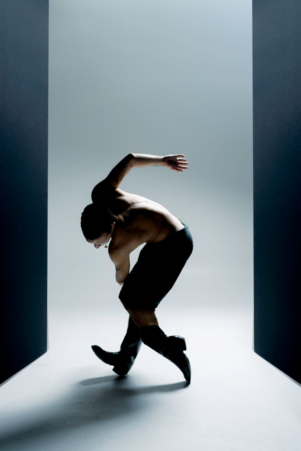 Dynamic sequence showing a figure performing fluid dance movements in a stark studio with dramatic side lighting.