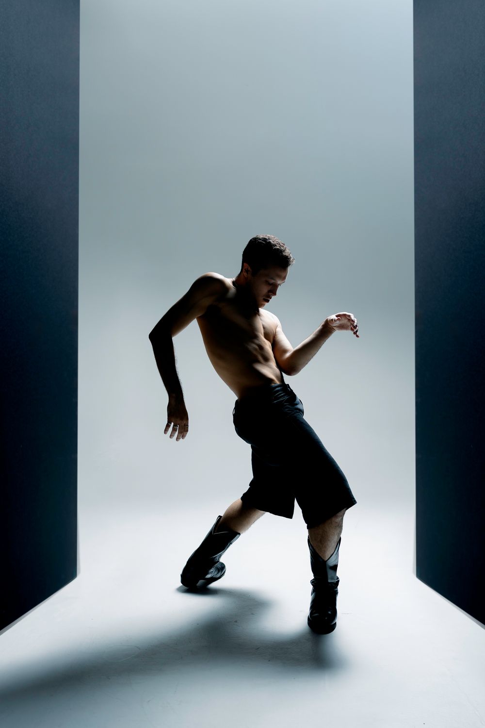Artistic dance sequence capturing a performer's expressive movements against a white backdrop with strong shadows.