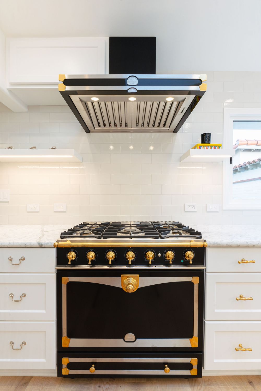 Black and gold luxury gas range with brass accents and white cabinetry in modern kitchen design.