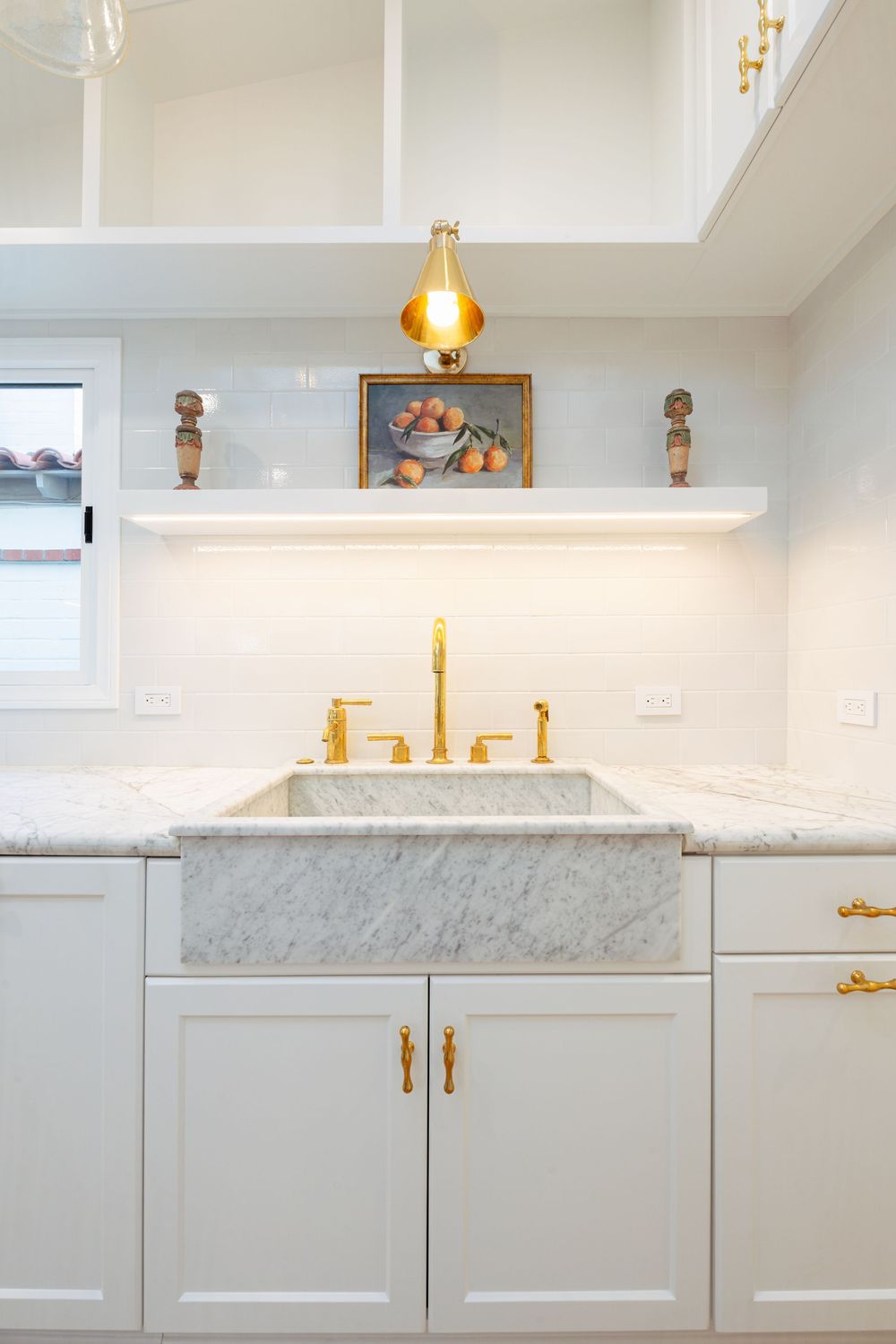 Modern white kitchen cabinets with marble countertops and gold hardware accents create an elegant, minimalist design.