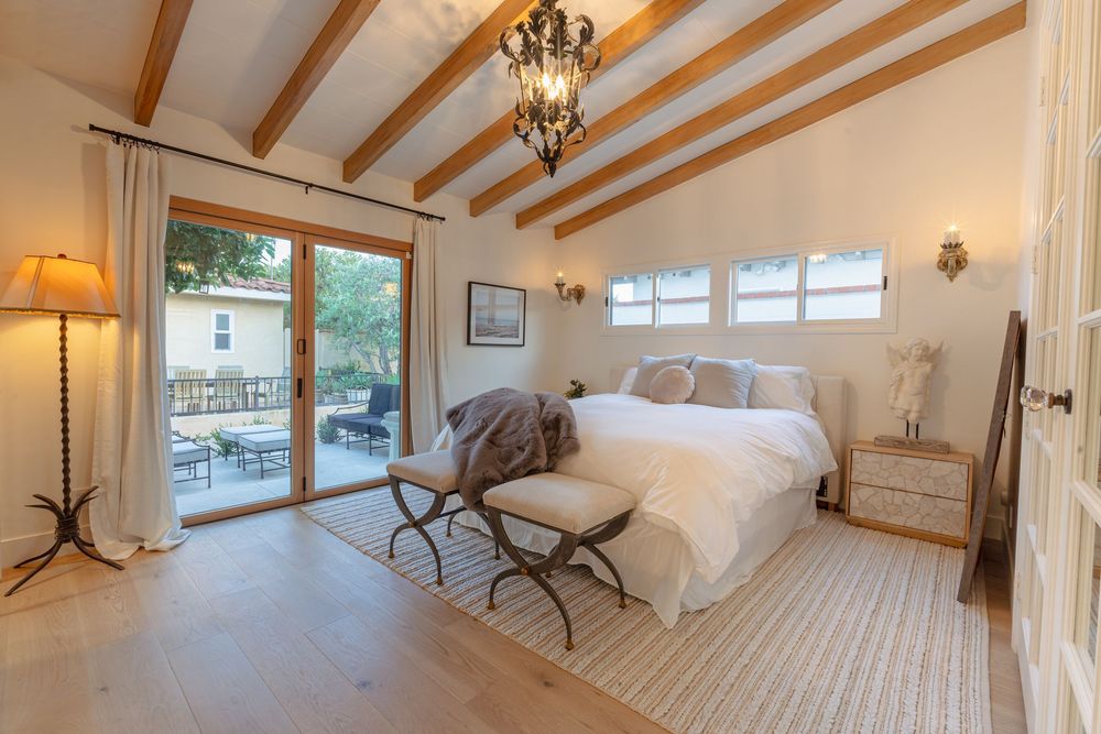Bright and airy room with exposed wooden beams, chandelier lighting, and panoramic windows showcasing natural light.