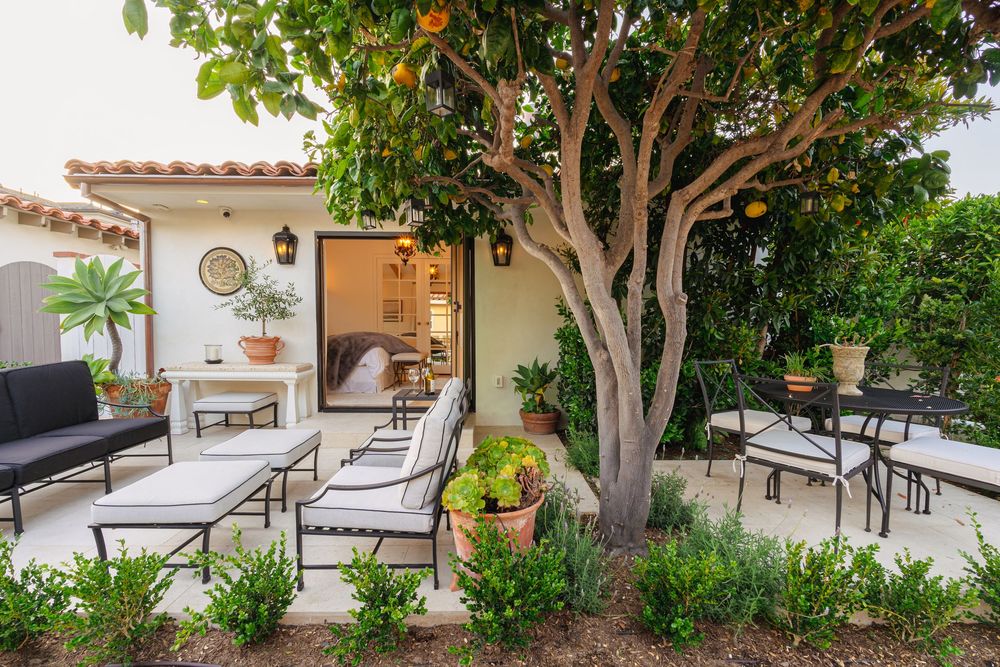 A luxurious Mediterranean villa patio features comfortable lounge chairs and a citrus tree creating a tranquil outdoor space.