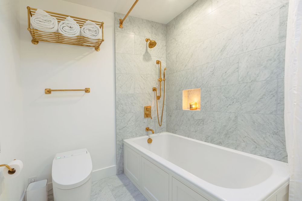 A modern white bathroom interior with gold fixtures and hardware showcases elegant design details and bright lighting.