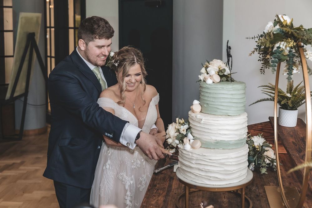 Close up natural moment of bride and groom cutting their wedding cake.