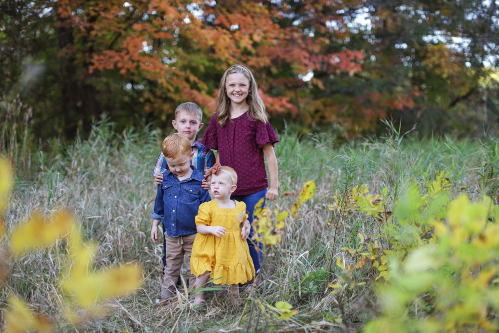 A scenic autumn outdoor setting with vibrant orange maple trees and yellow flowers in the foreground.