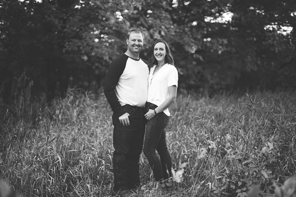 A series of black and white photographs showing joyful moments between two people in a grassy outdoor setting.