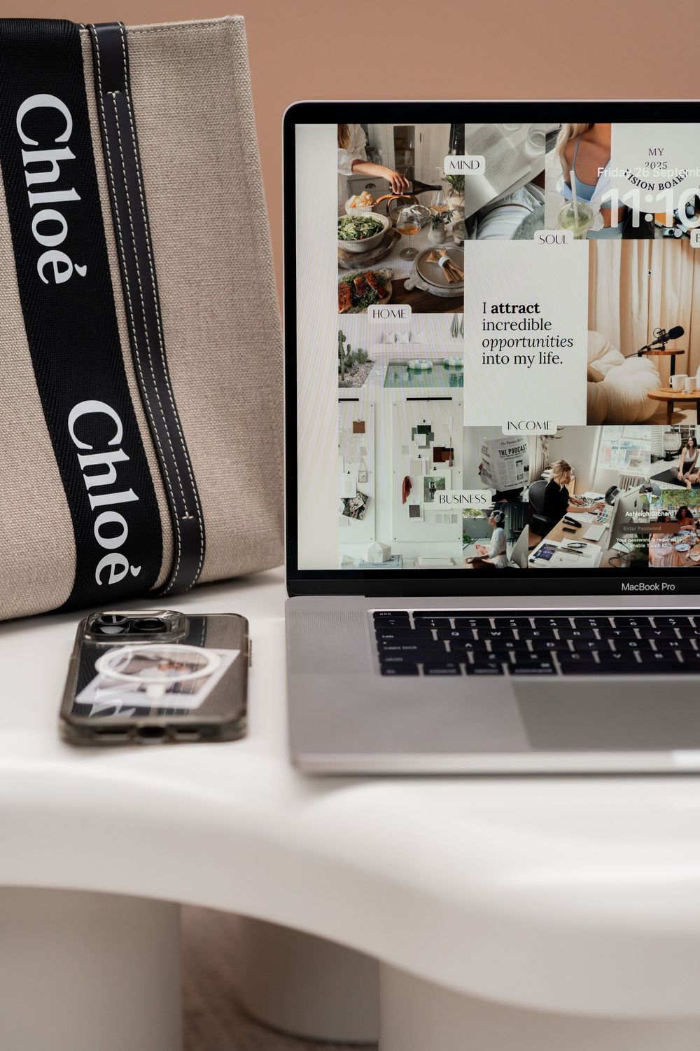 A sleek laptop workspace setup with a candle and decorative elements in muted neutral tones.