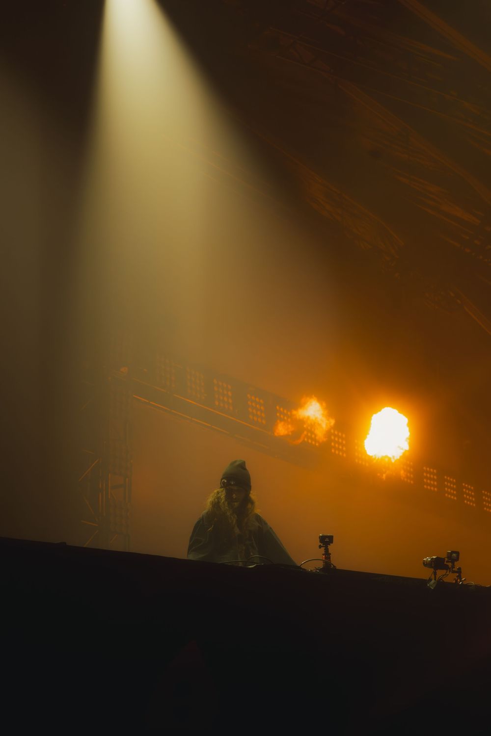 A dramatic silhouette of military personnel and equipment against an orange night sky with spotlights illuminating the scene.
