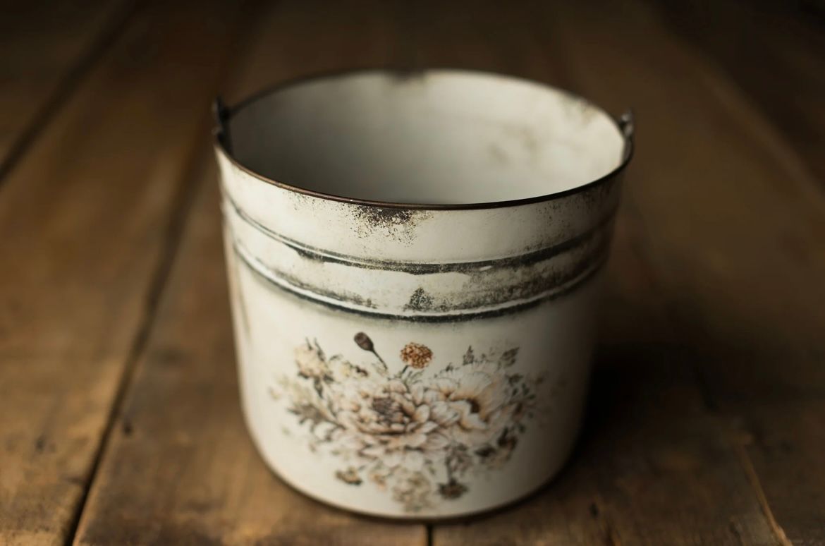 Vintage floral enamelware bowls arranged in a row on rustic wooden surface with warm lighting.