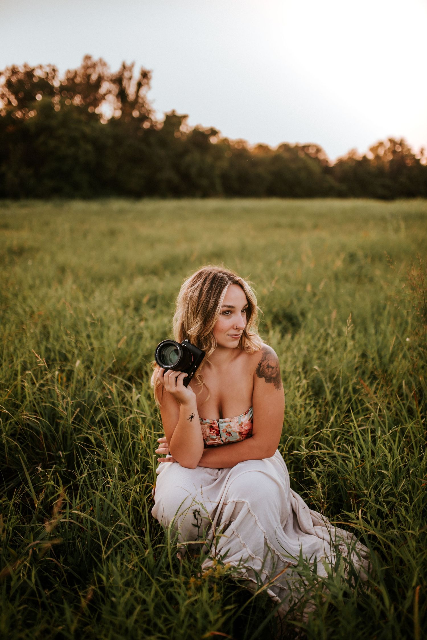 Branding Photo of a photographer in a field at sunset with her camera in her hand in Clarksville, Tennessee.