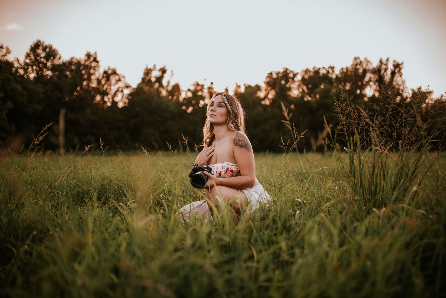 Branding photo of a photographer in a field during sunset with her camera in her hand in Clarksville, Tennessee.