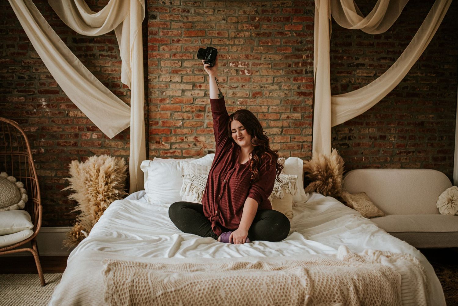 Branding photo of a photographer on a bed with her hair behind her in a Studio in Clarksville, Tennessee with her camera.