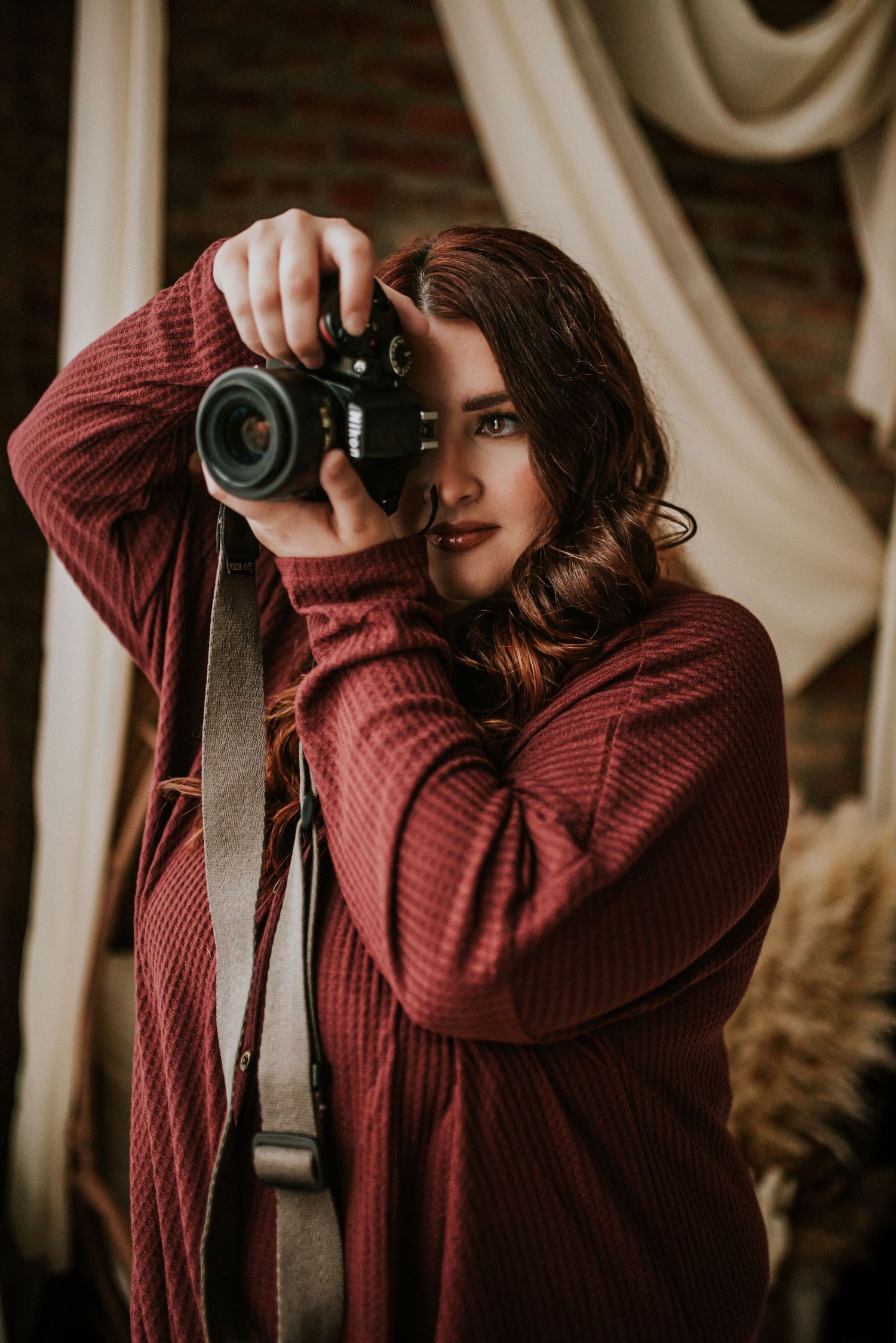 Branding photo of a photographer in the studio with her camera to her eye in Clarksville, Tennessee.