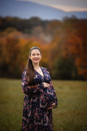 Charlottesville maternity photoshoot featuring mom in floral gown against a colorful fall bokeh backdrop, from baby photographer.