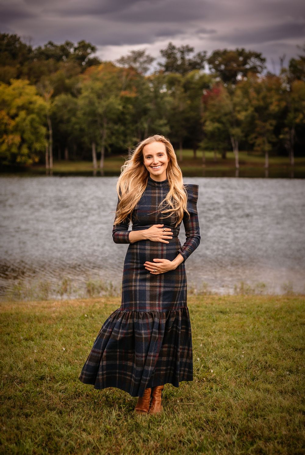 Gorgeous expectant mother with a plaid dress  cradles her bump against a fall backdrop by Charlottesville maternity photographer.