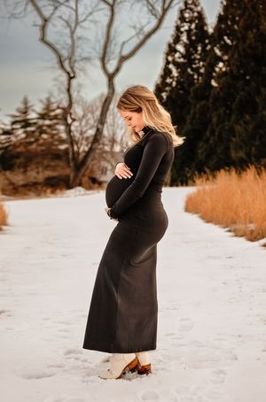 Lovely pregnant lady dressed in sleek black cradles bump at Boar's Head Inn and resort, captured by Charlottesville maternity photographer.