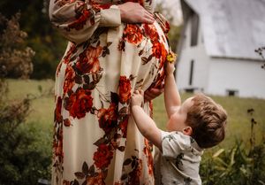 Charlottesville photographer, maternity, family, newborn, baby, big brother holds a yellow flower against his mother's pregnant belly.