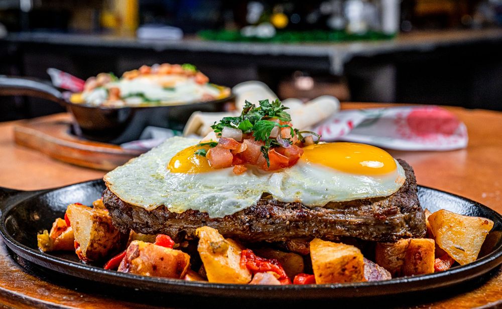 A sizzling skillet of Korean bibimbap topped with a sunny side up egg, vegetables, and gochujang sauce.