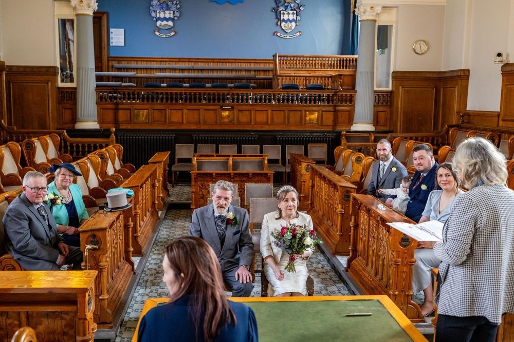 edding guests seated in the ceremony room at Southport Town Hall as the bride and groom wait at the front.