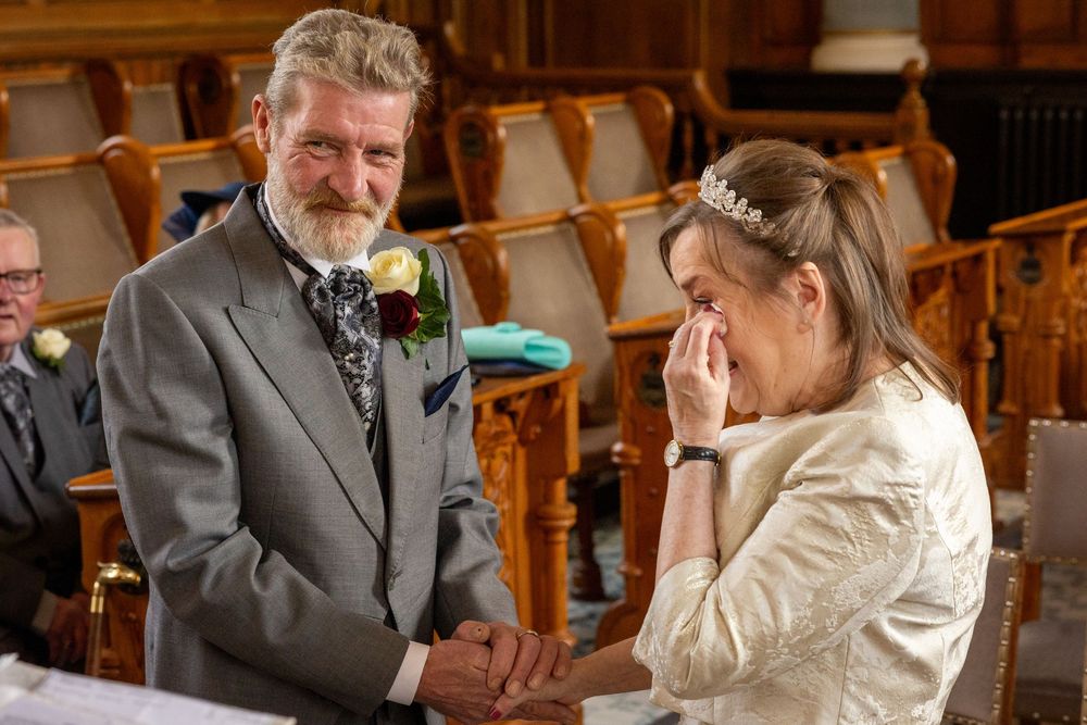 Bride wipes away happy tears while holding hands with the groom during their Southport Town Hall wedding ceremony.