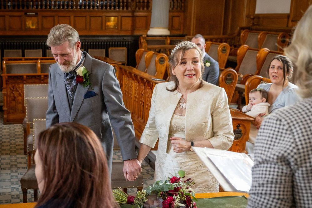 Bride and groom smile during their Southport Town Hall wedding ceremony, surrounded by close family.