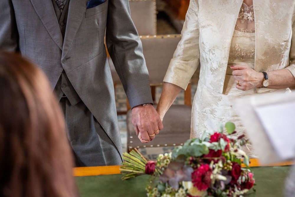 Bride and groom hold hands beside their bouquet during their small Southport Town Hall wedding ceremony.