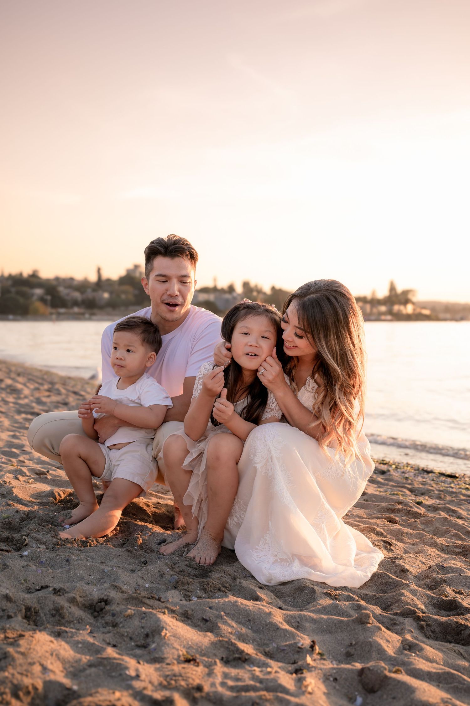 A family shares joyful moments together while sitting on a sandy beach at sunset.