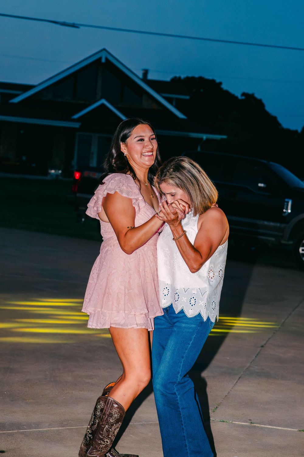 People dancing together in casual outfits with cowboy boots at sunset.