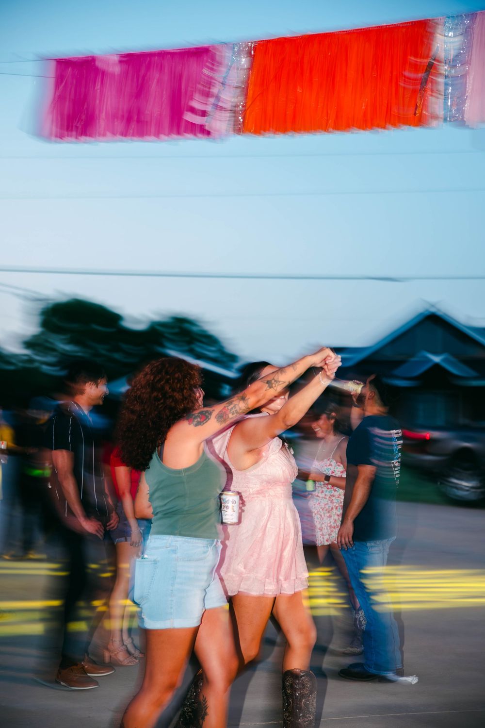 Blurred motion shot of people dancing in colorful outfits at an outdoor event.