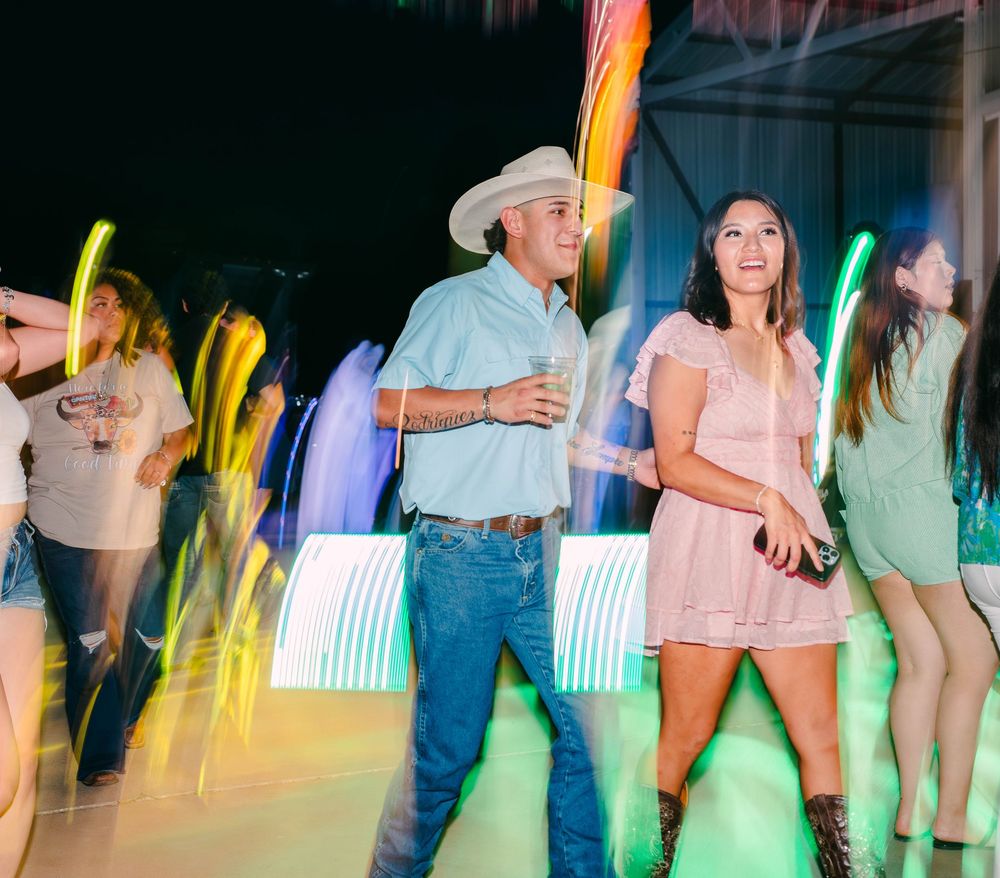 People dancing under colorful lights at a nighttime outdoor gathering.