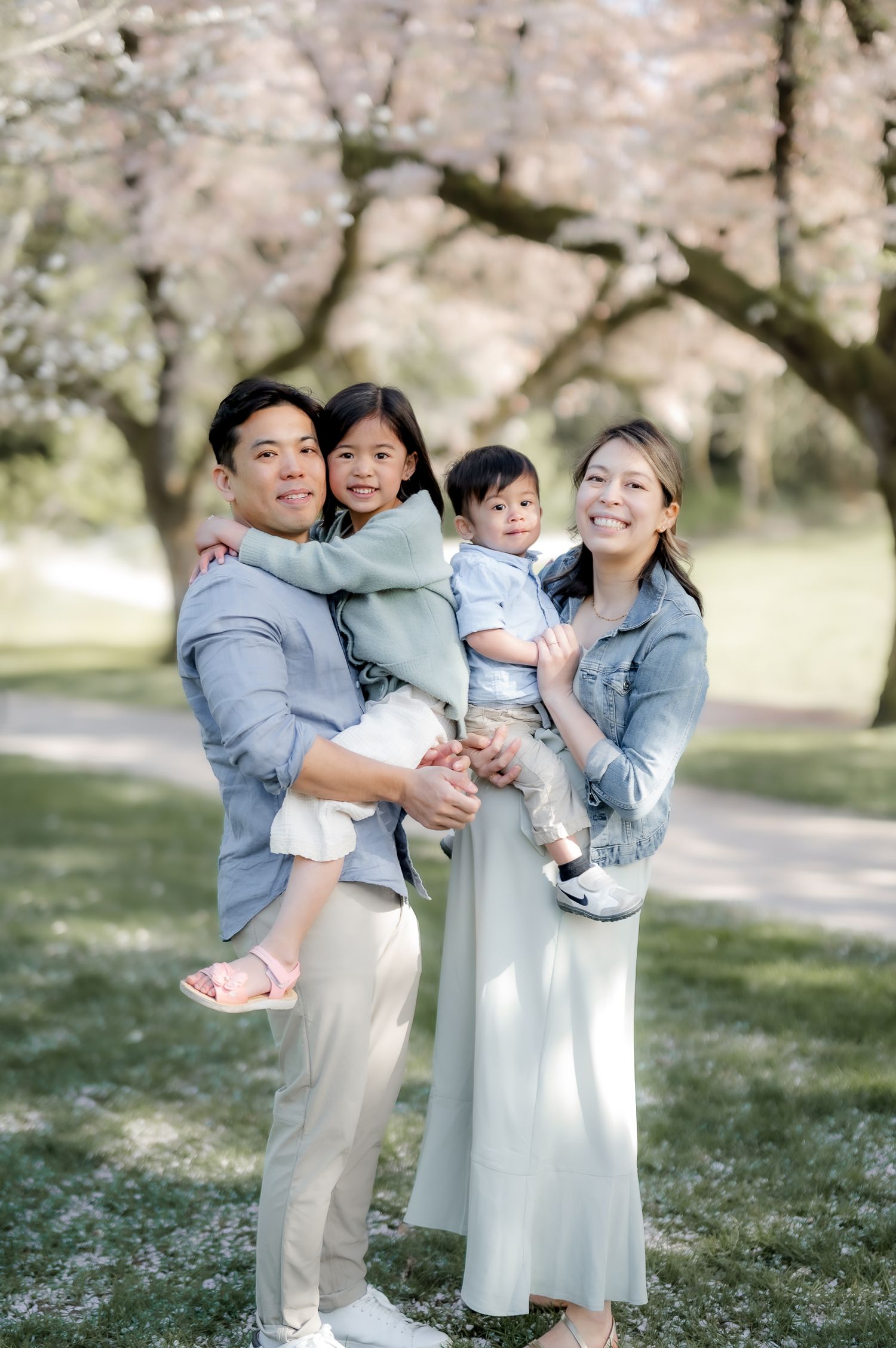 Family shares joyful moments together in a spring garden with blooming cherry blossoms in the background.