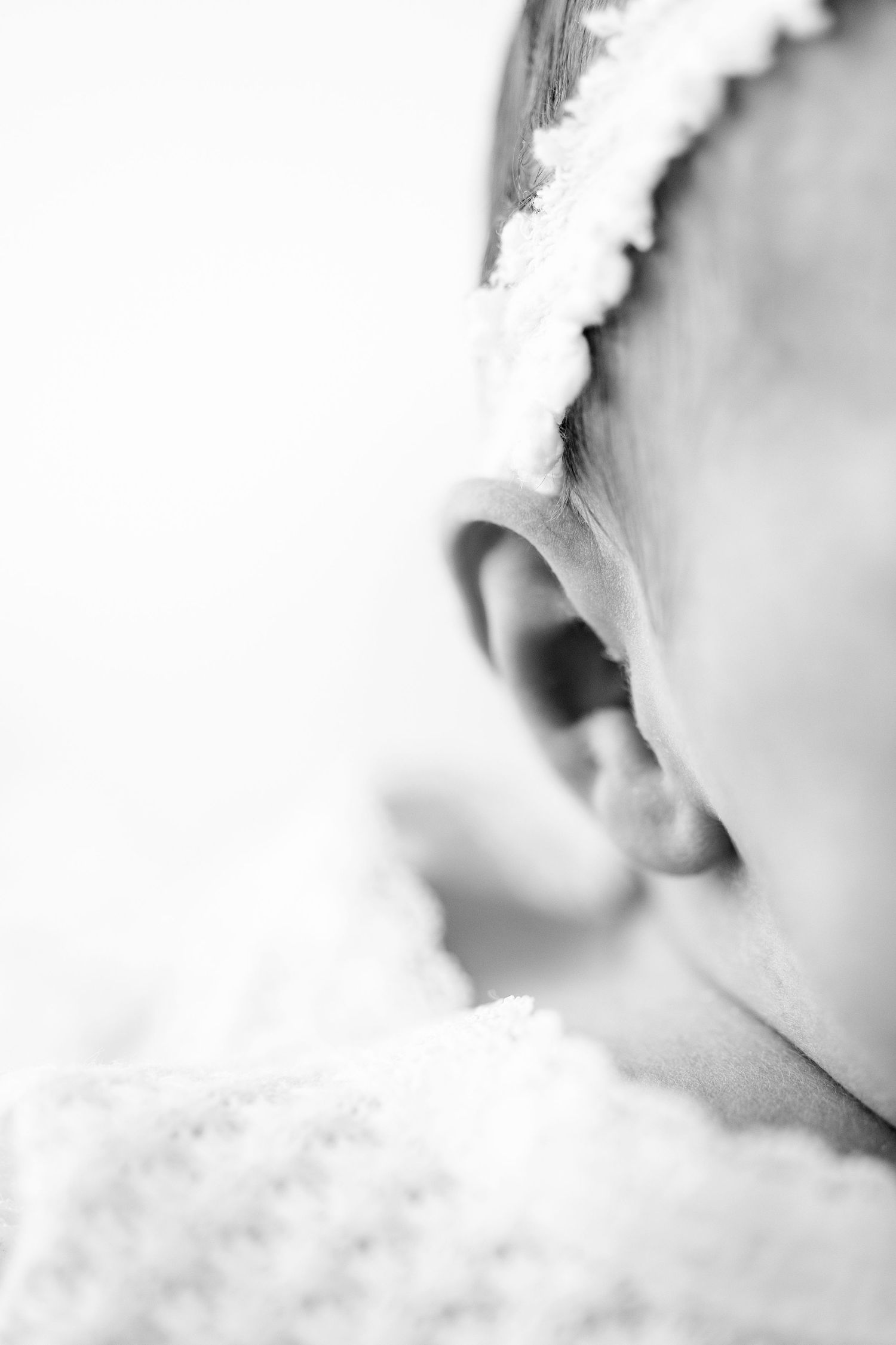 Close-up black and white photo of a tiny baby foot resting in an adult's cupped hands.
