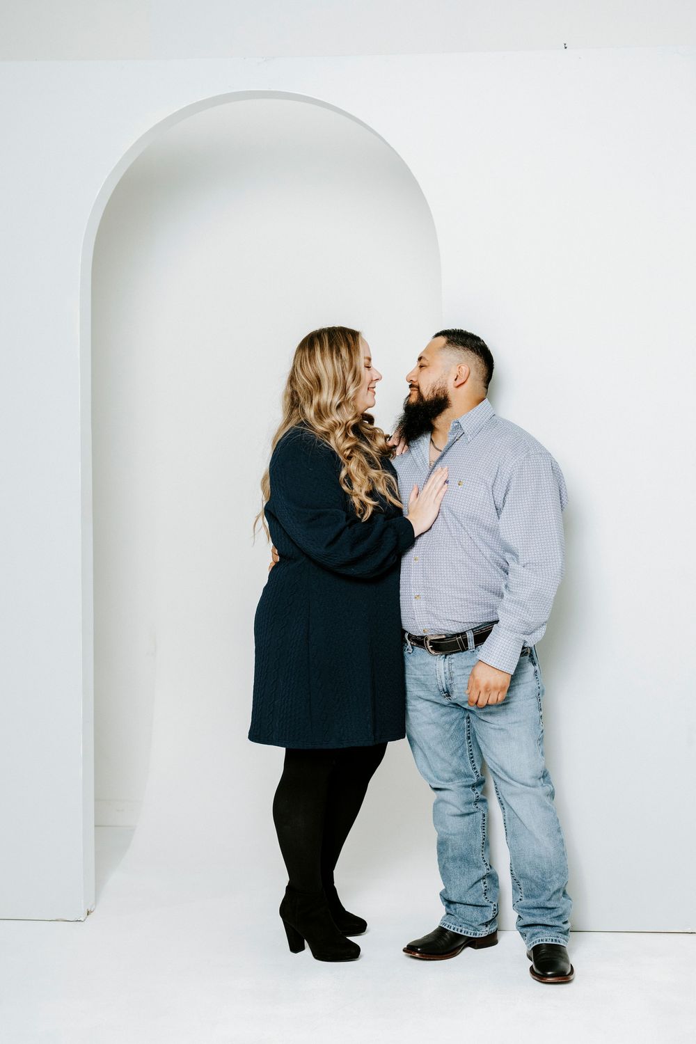 A sequence of minimalist photos showing a couple posing against a white wall with an arched doorway.
