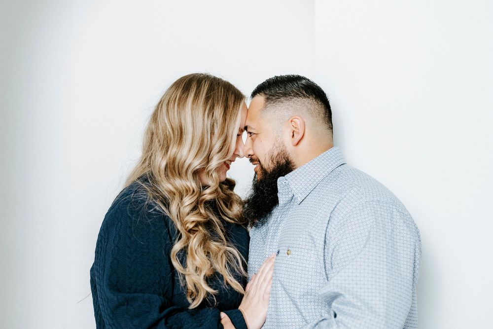 A romantic couple shares a tender moment against a white backdrop in a series of intimate photographs.