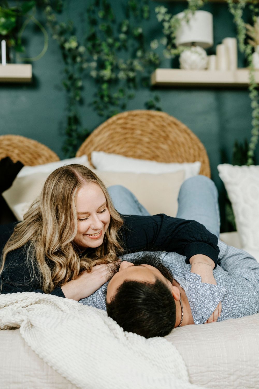 A couple shares intimate moments while relaxing together on a cozy bed with white linens.