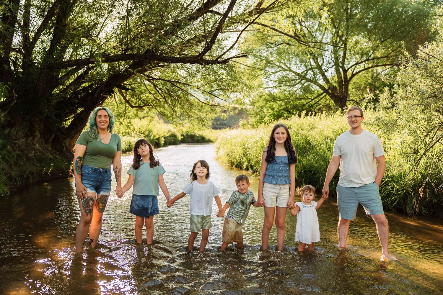 Family of seven wearing sage green and cream outfits during a spring photo session in Colorado Springs.