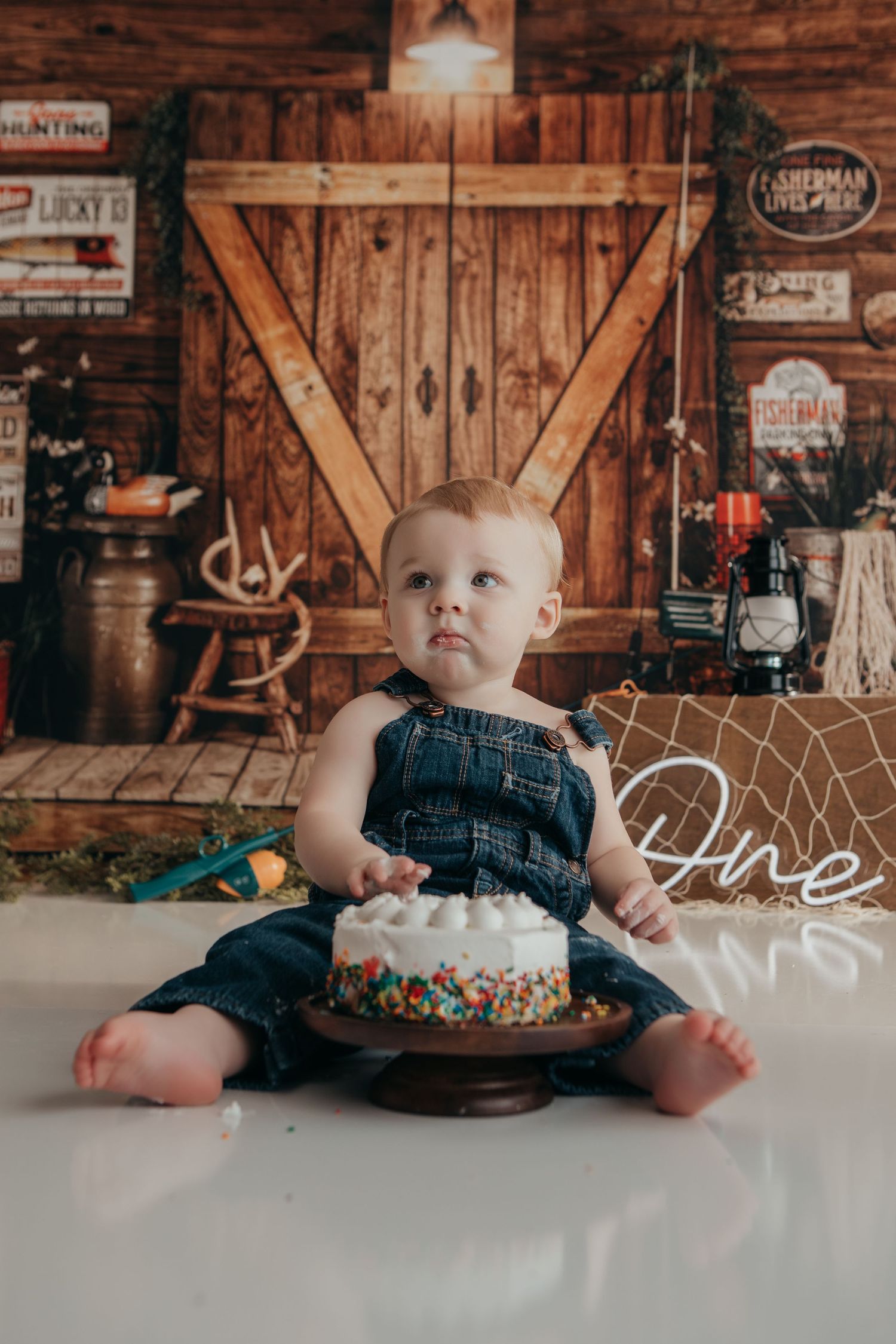 Rustic barn-themed baby photo session with wooden backdrop and vintage decorations.